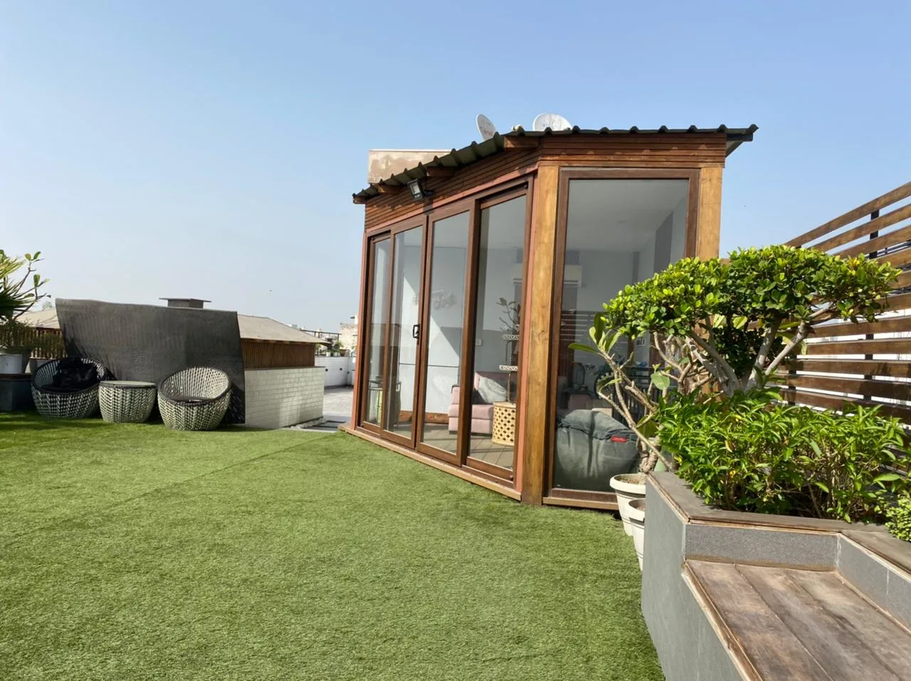 Compact garden cabin beside an open rooftop lawn